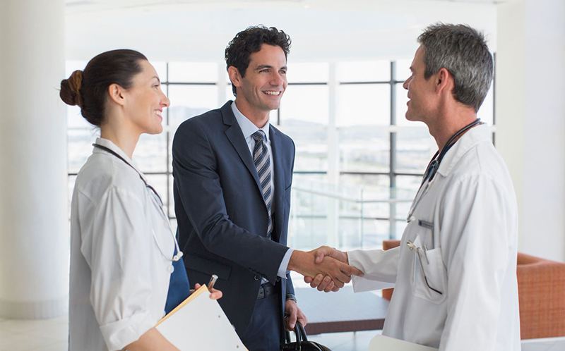 Representante médico saludando a dos profesionales de la salud